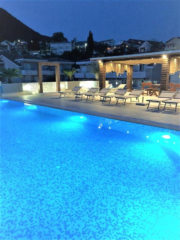 a large swimming pool with chairs and a building at Apartment Sun Village Goran in Herceg-Novi