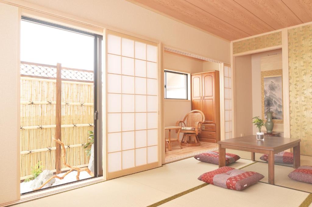 ein Wohnzimmer mit einem Tisch und einem großen Fenster in der Unterkunft Shirakabanoyado - Osakajo in Osaka