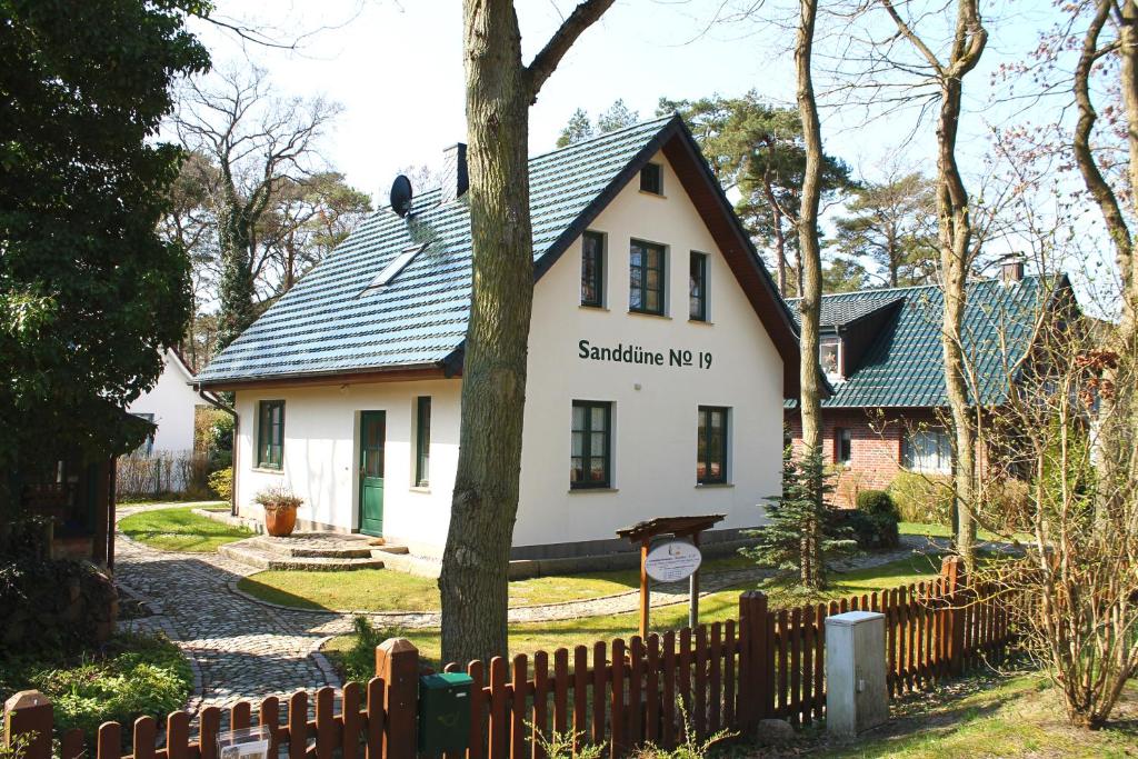 a white house with a black roof and a fence at Ferienhaus "Sanddüne No.19" in Boltenhagen