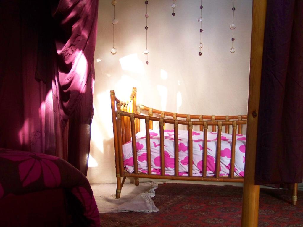 a baby crib in a room with pink sheets at la boutique de laurence in Ségrie-Fontaine