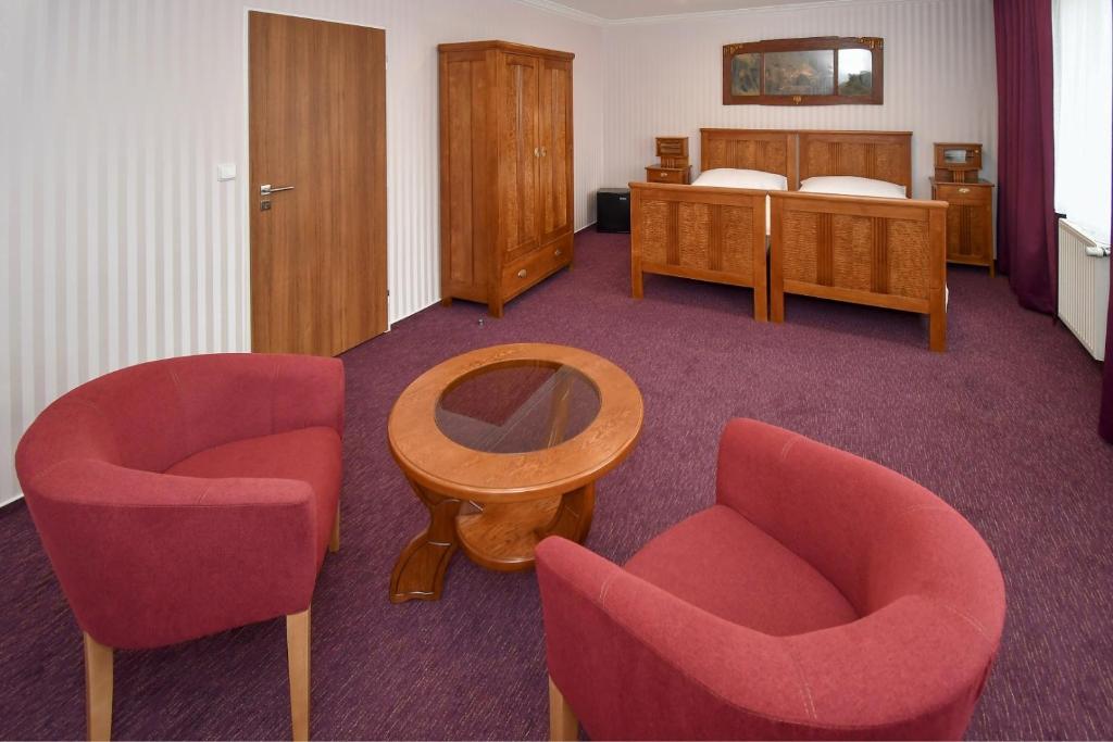 a room with two chairs and a table and a bed at Hotel Sonata in Hradec nad Moravici