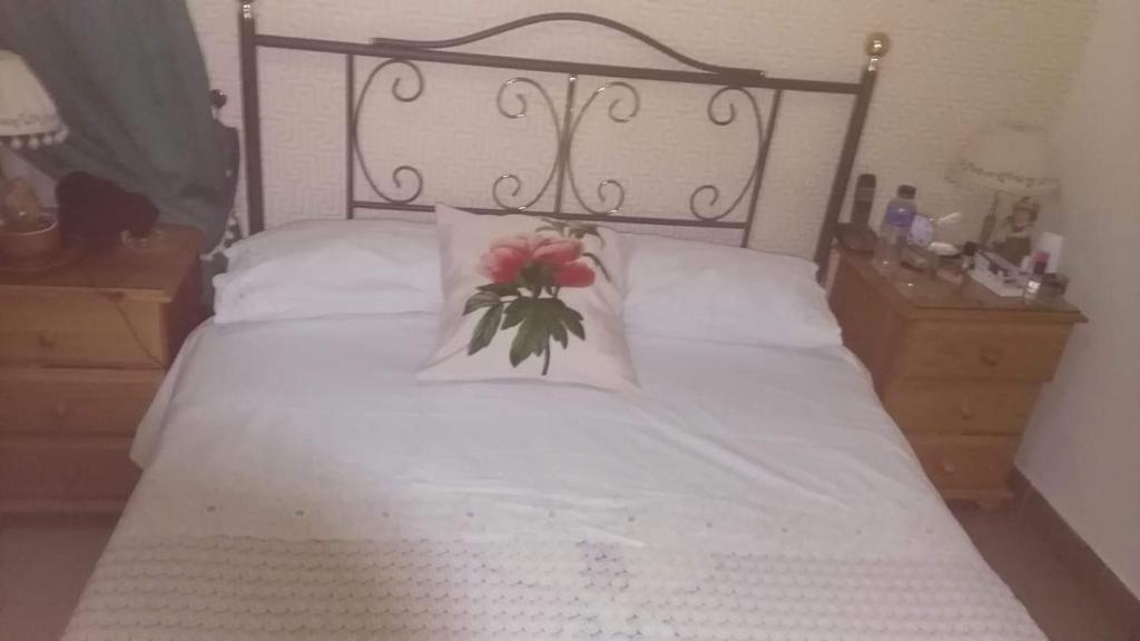 Un dormitorio con una cama blanca con una flor. en Casa Rural Anzo, en Gáldar