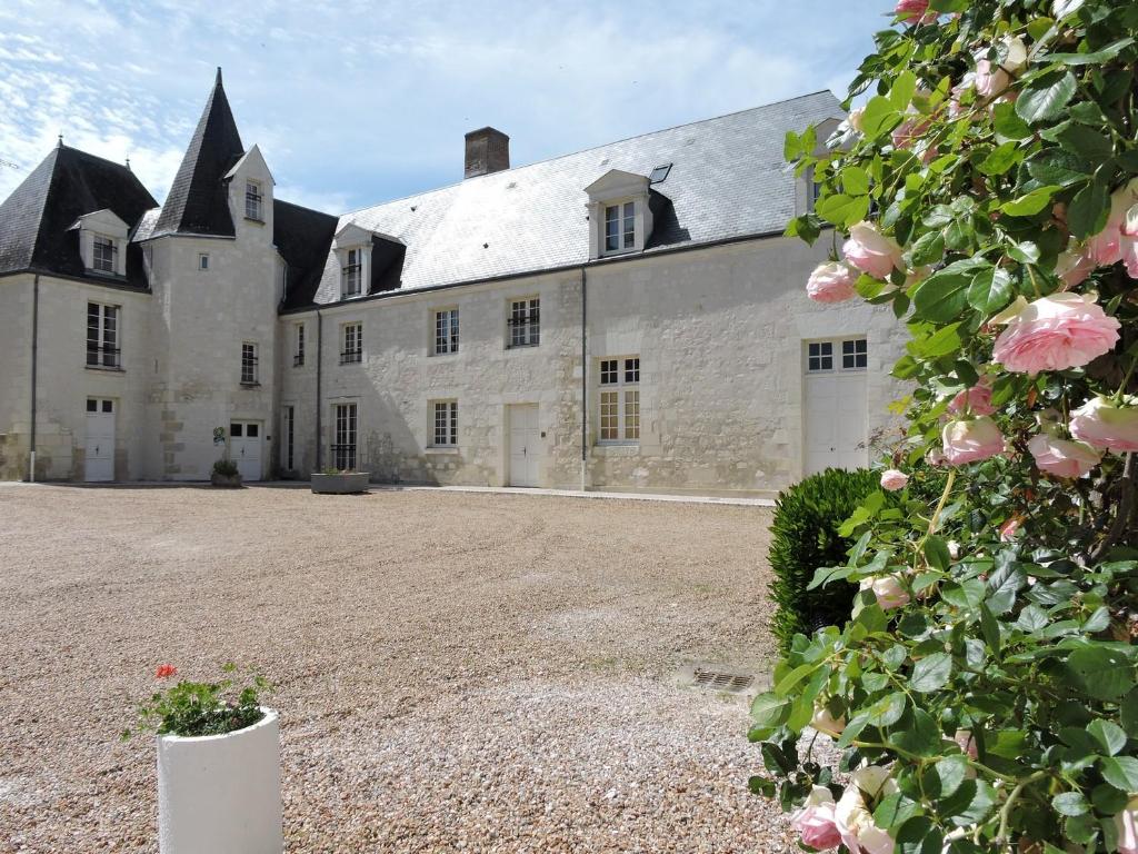 un gran castillo blanco con rosas rosas delante de él en Les Berges, en Mareuil-sur-Cher