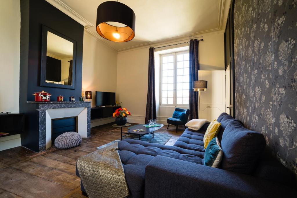 a living room with a blue couch and a fireplace at Le Grand Appartement d'Albusse in Sarlat-la-Canéda