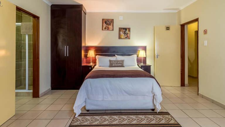 a bedroom with a bed and a walk in shower at Gannet Place Guest House in Hazyview