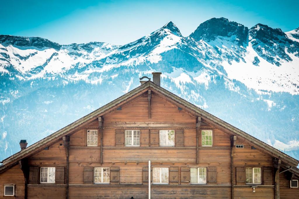 a log cabin with snow covered mountains in the background at Gasthaus Brünig Kulm in Brunig