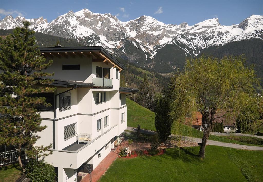 a white building with snow capped mountains in the background at Haus Schmid in Tobadill