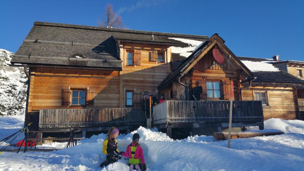 two people standing in the snow in front of a log cabin at Thomahofhuette in Tauplitzalm