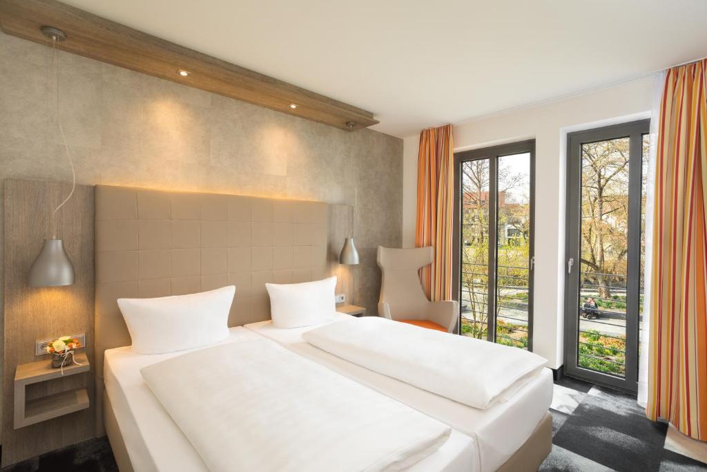 a bedroom with a large white bed and a window at Hotel Krämerbrücke Erfurt in Erfurt