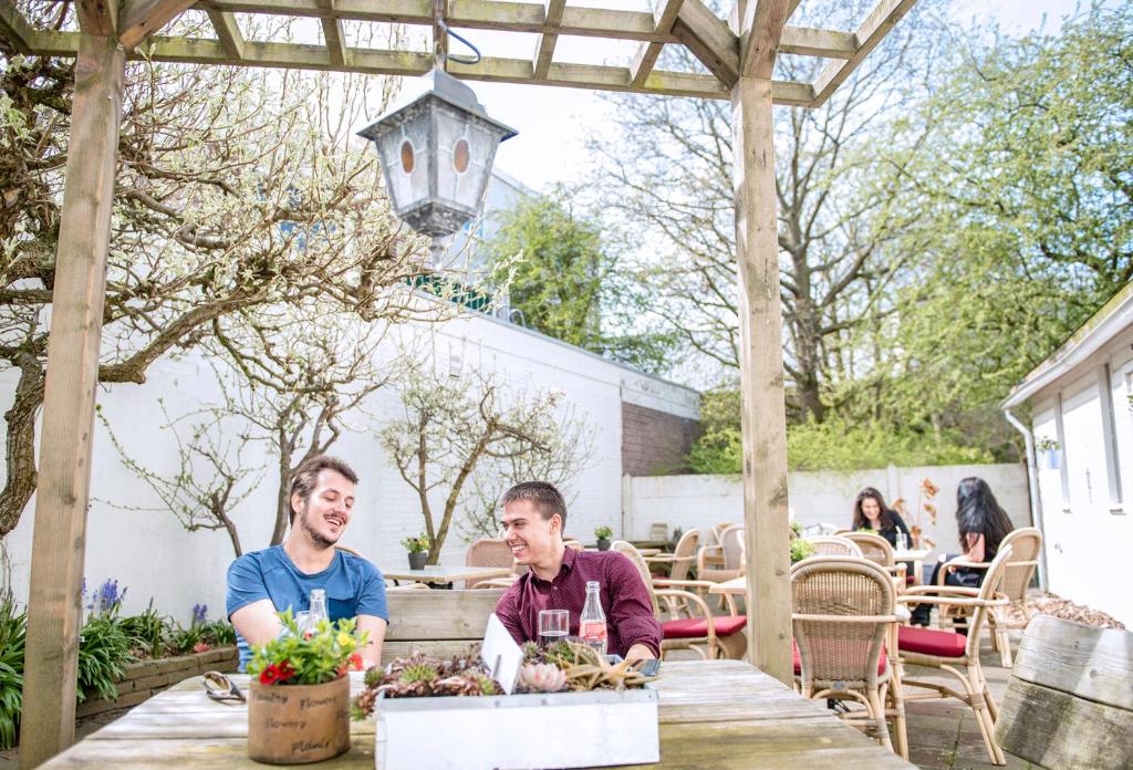 two men sitting at a table under a pergola at City2Beach Hotel in Vlissingen