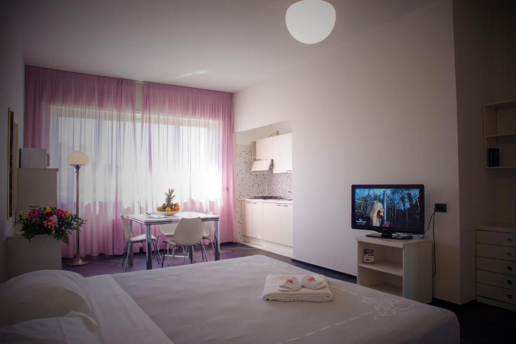 Residence Hotel Torino Uno في تورينو: غرفة نوم بسرير وطاولة وتلفزيون