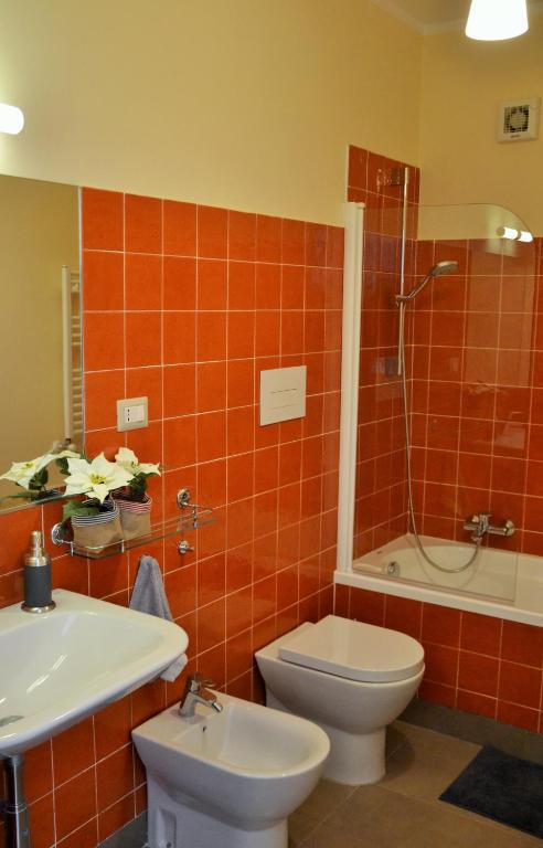 W wyłożonej pomarańczowymi kafelkami łazience znajduje się toaleta i prysznic. w obiekcie Casa Arcoiris w mieście Neapol