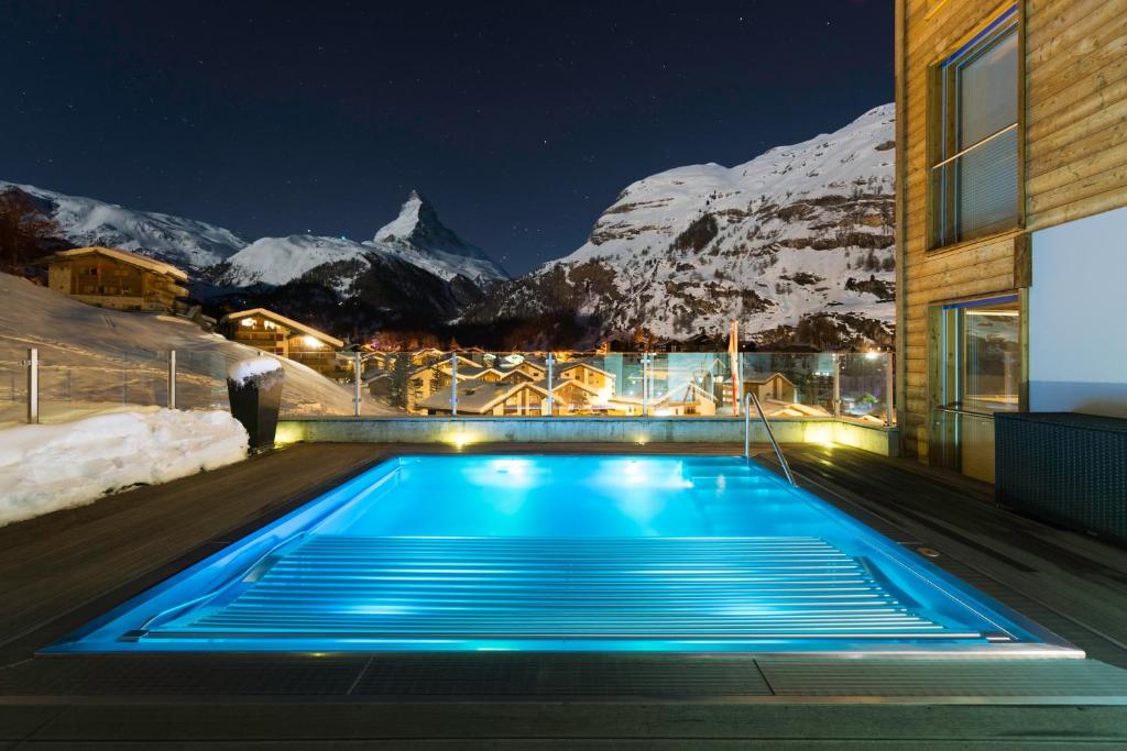una piscina di fronte a una montagna di notte di Chalet Nepomuk a Zermatt