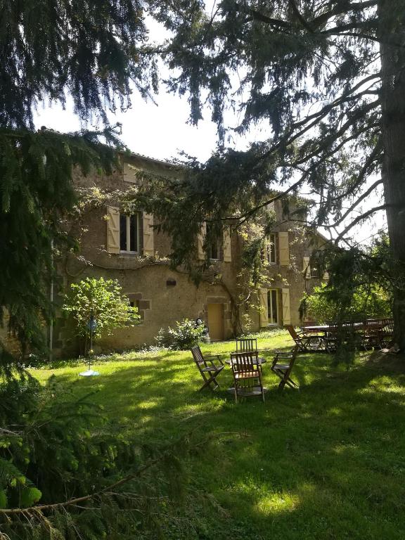 a large stone building with benches in the grass at le Logis d'Argenson in Beaulieu-sous-Parthenay