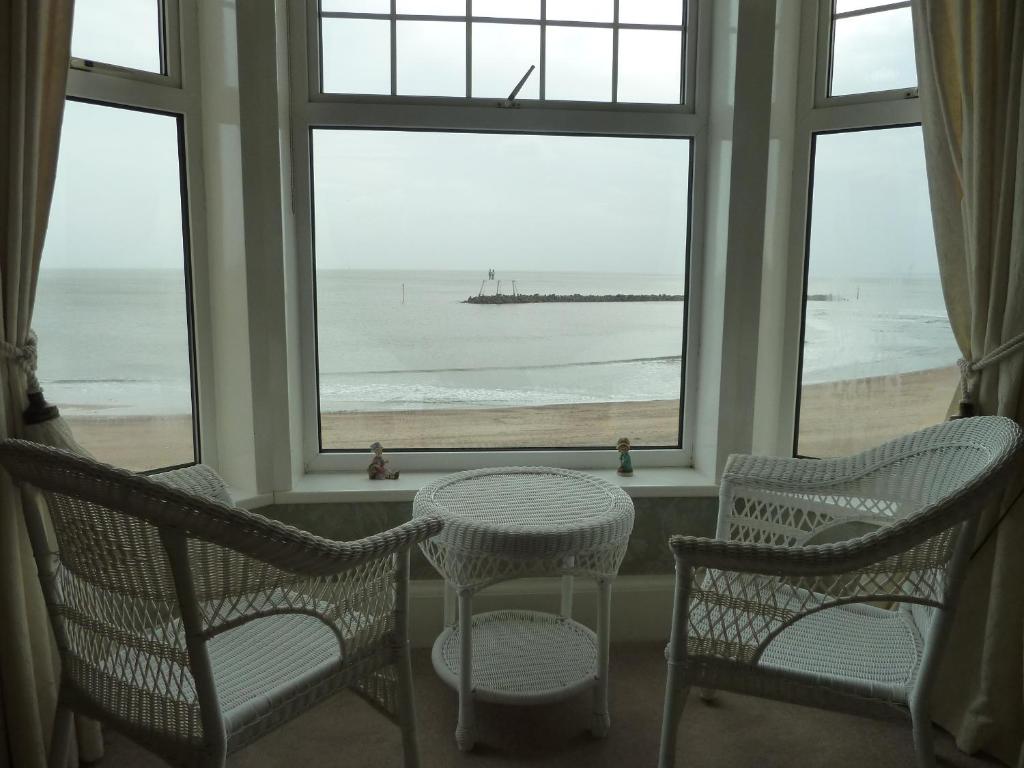 a room with three chairs and a window with a view of the beach at Captains Lodge in Newbiggin-by-the-Sea