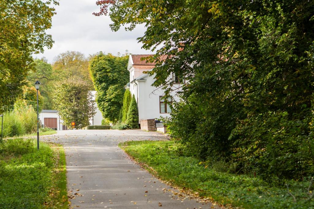 a road leading to a white house with trees at Stavsjö Herrgårdsflygel in Stavsjo