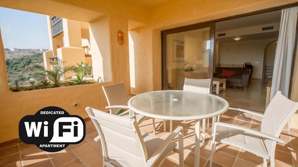 a dining room with a glass table and white chairs at Coto Real Naxos 321 in Manilva