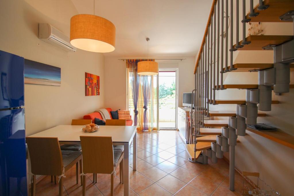 een woonkamer met een trap en een tafel en stoelen bij Denis in Novigrad Istria