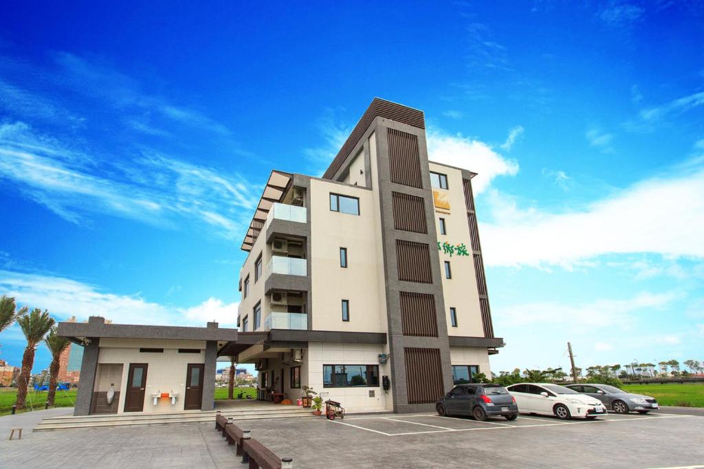 a building with cars parked in a parking lot at Urban Oasis Inn in Luodong