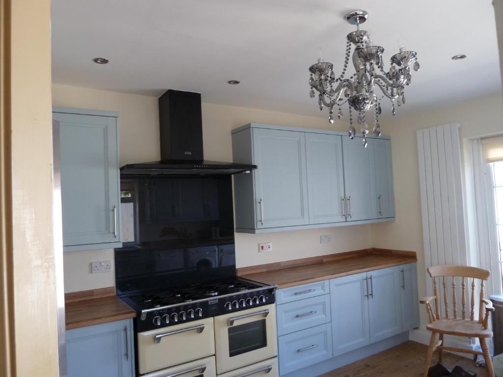 a kitchen with a stove and white cabinets and a chandelier at Captains Lodge in Newbiggin-by-the-Sea