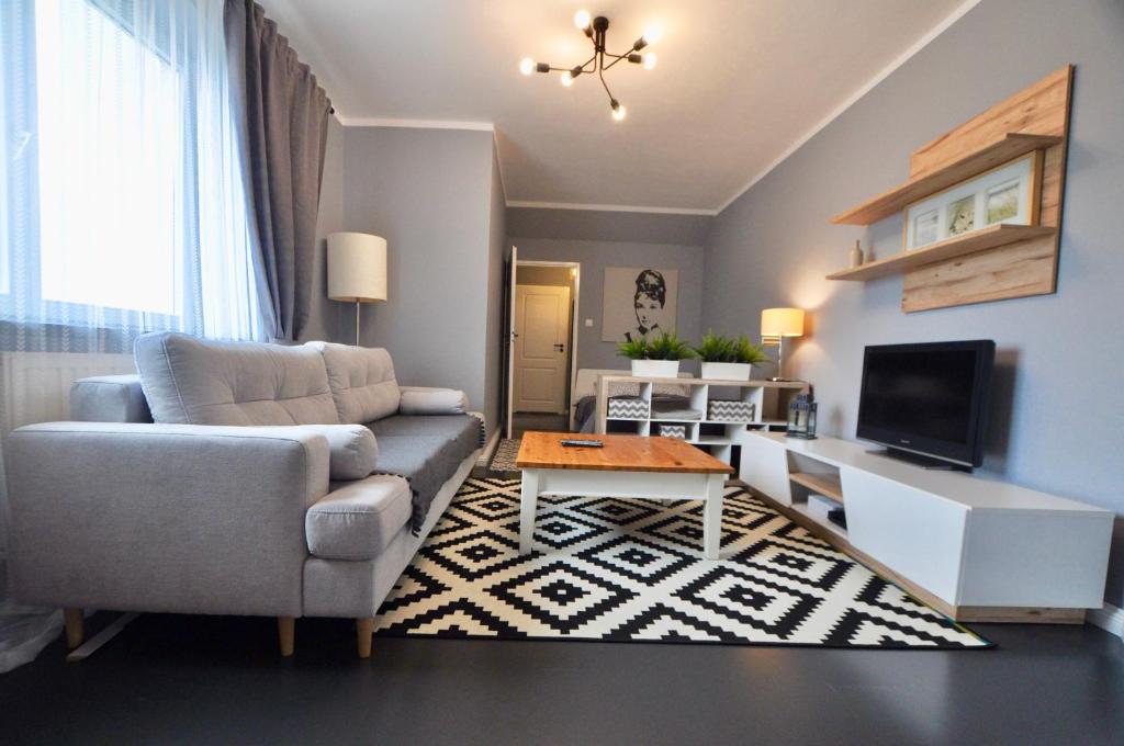 ein Wohnzimmer mit einem Sofa und einem TV in der Unterkunft Abrahama Apartment in Warschau