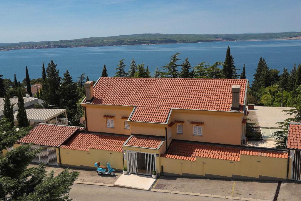 a house with a red roof with a lake in the background at Apartments Casa Mia in Dramalj