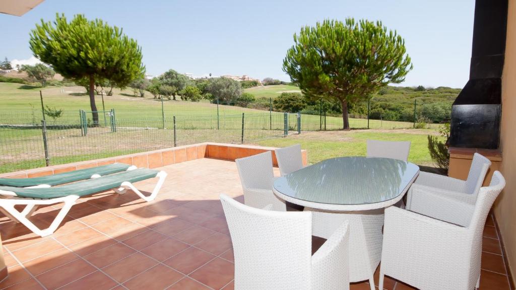 een patio met een tafel en stoelen en een bank bij Villas del Golf 23 in Manilva