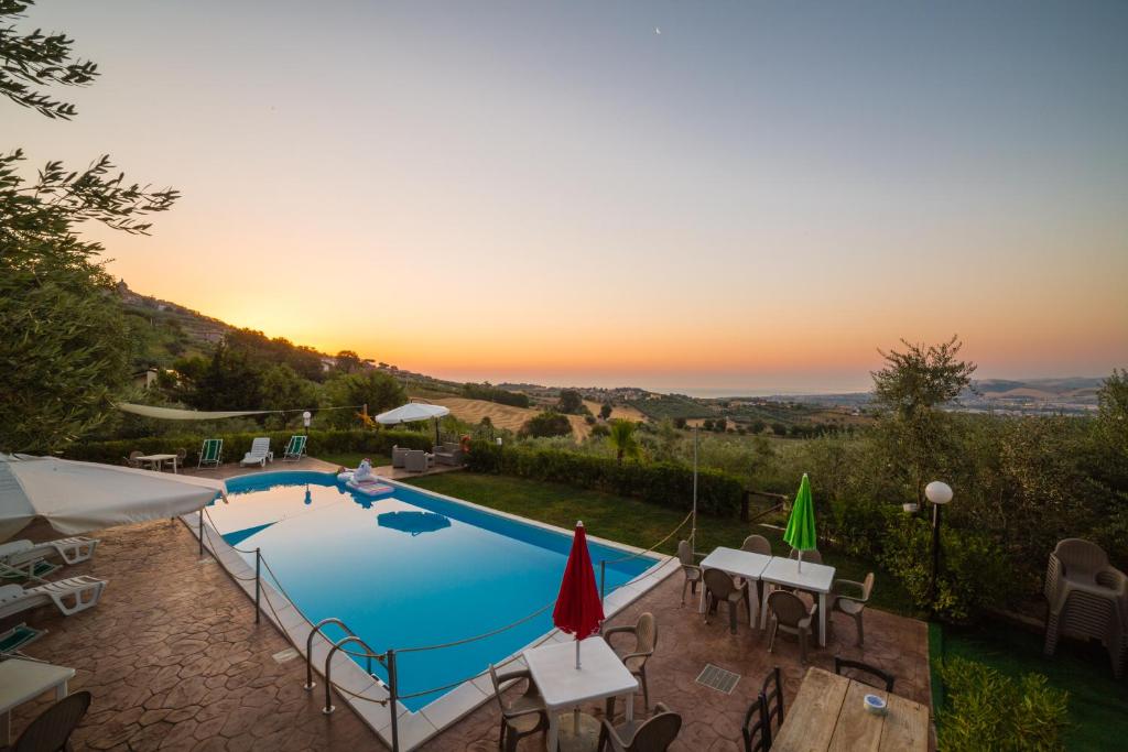uma piscina com mesas e cadeiras e um pôr-do-sol em Casale delle Rose Casa Vacanze em Montepagano