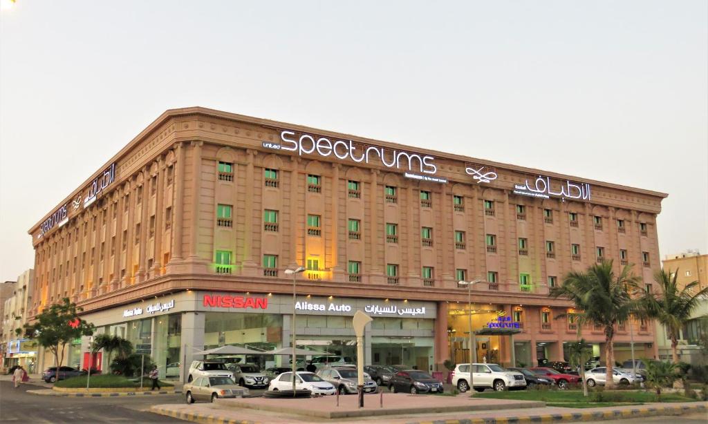 a large building with cars parked in a parking lot at Spectrums Residence Jeddah in Jeddah