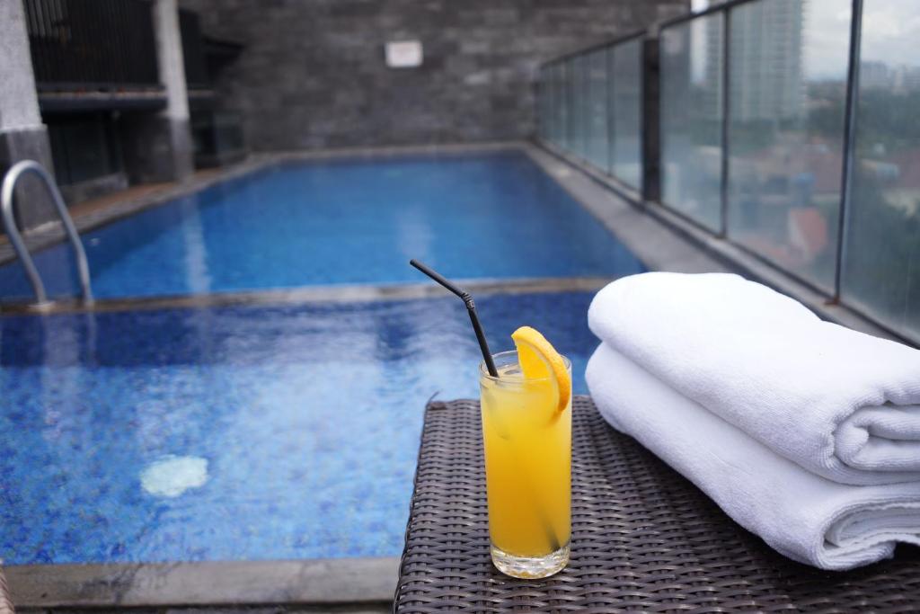 a drink sitting on a table next to a swimming pool at Liberta Hotel Kemang in Jakarta