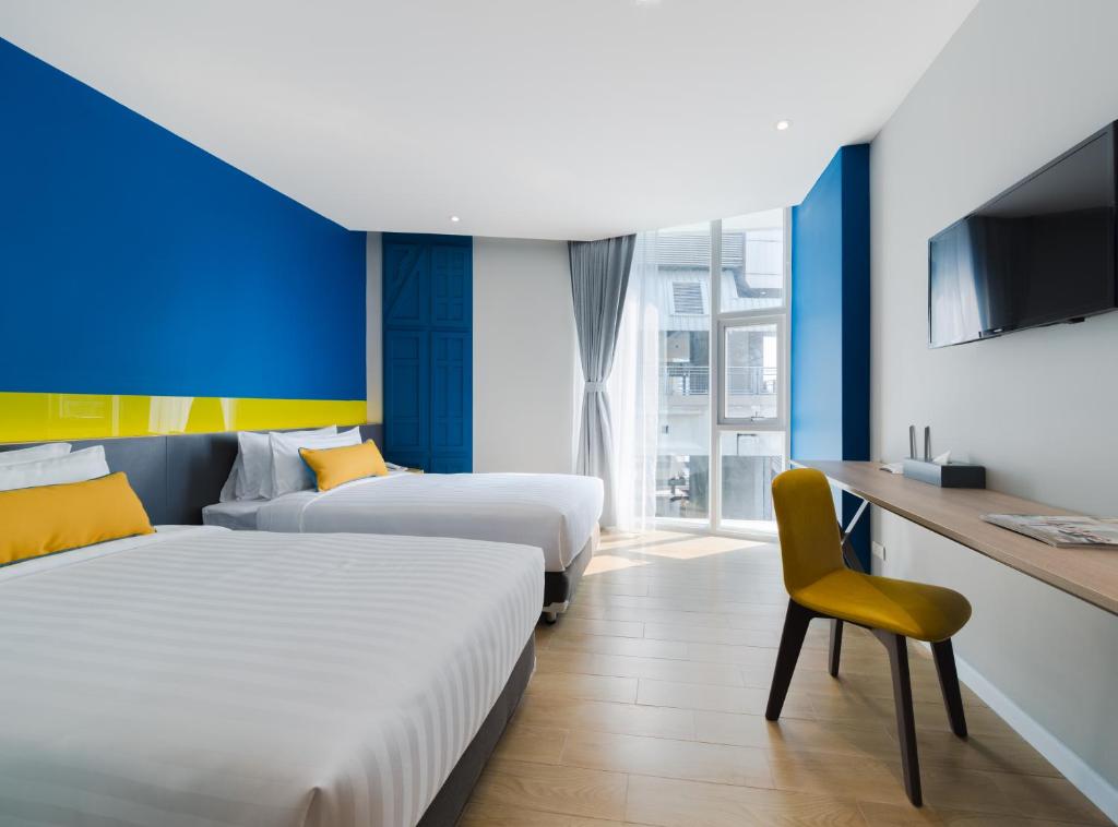 a hotel room with two beds and a tv at Hotel Tranz in Bangkok