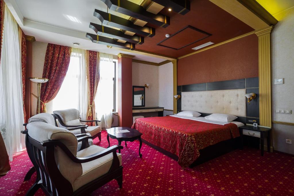 クラスノダールにあるTroy Hotelのベッド1台と椅子2脚が備わるホテルルームです。
