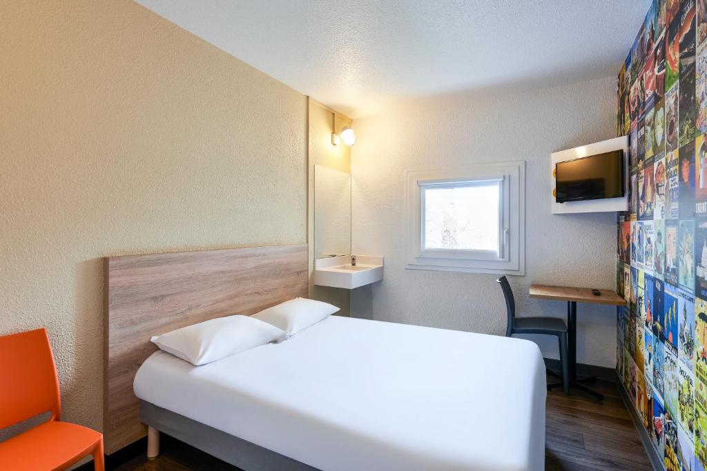 Pokój hotelowy z białym łóżkiem i oknem w obiekcie hotelF1 Chartres w mieście Le Coudray