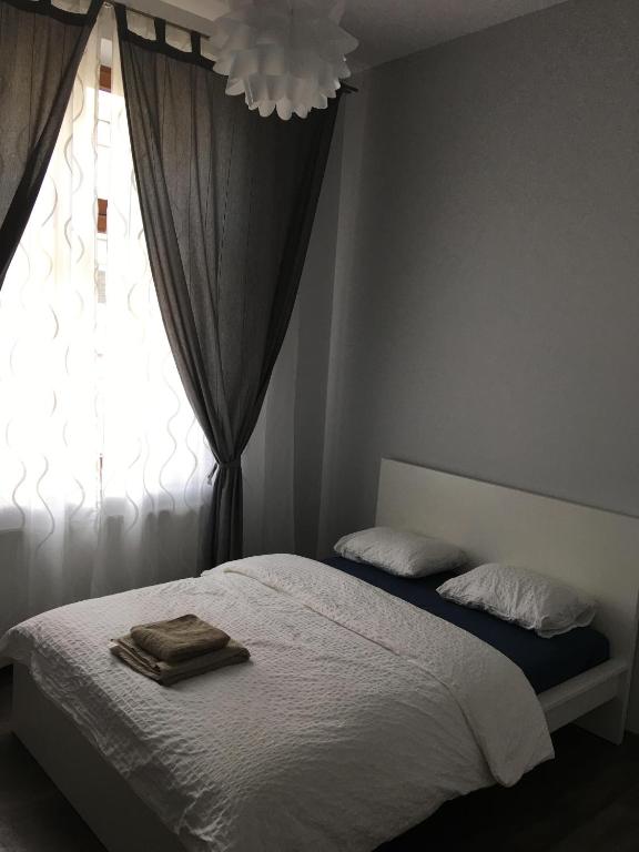 a bedroom with a bed with white sheets and a window at Ametyst Apartments in Krakow