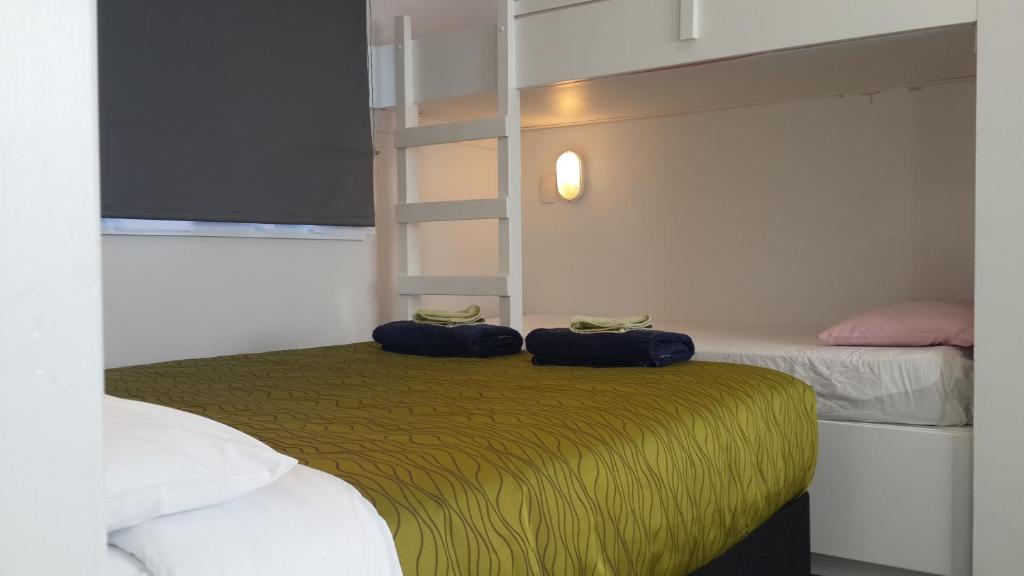 a bedroom with two beds and two blue bags on the bed at Cosy Cottage Thermal Holiday Park in Rotorua