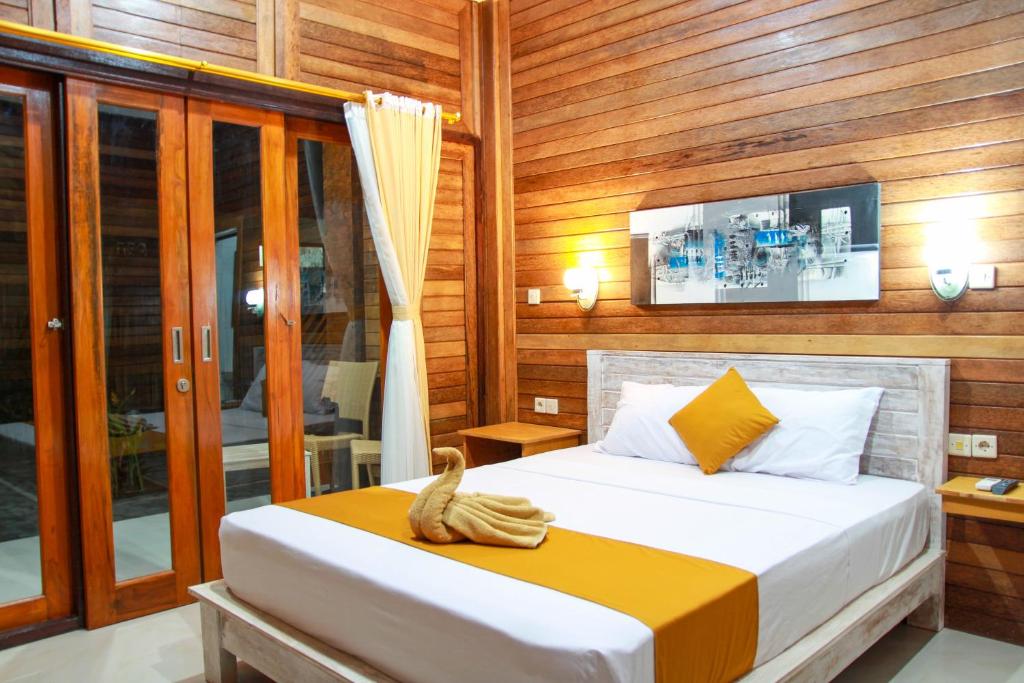 1 dormitorio con 1 cama con pared de madera en D'Tegal House, en Nusa Lembongan