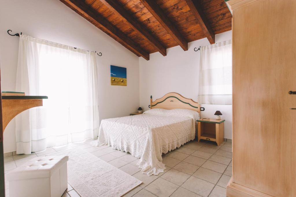 a bedroom with a bed in a room with windows at Sole d'Estate Agriresidence in Costa Rei