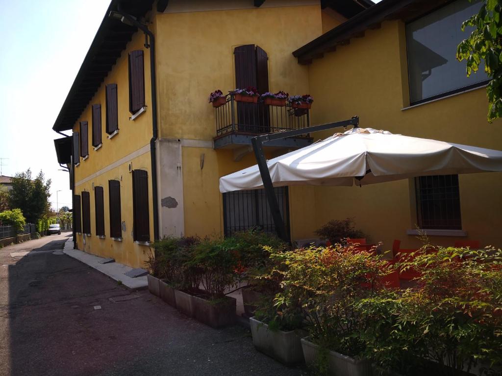 un bâtiment jaune avec un parapluie devant lui dans l'établissement La Stazione Camere Caffè, à Castiglione delle Stiviere