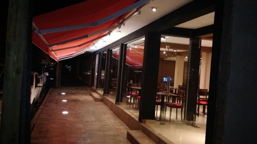 un restaurante con toldo rojo, mesas y sillas en Hotel Isella en Salta