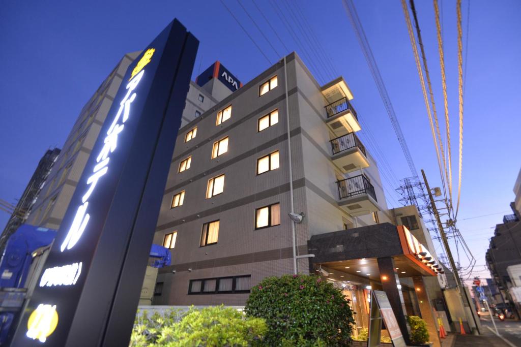 un edificio con una señal delante de él en APA Hotel Isehara-Ekimae, en Isehara