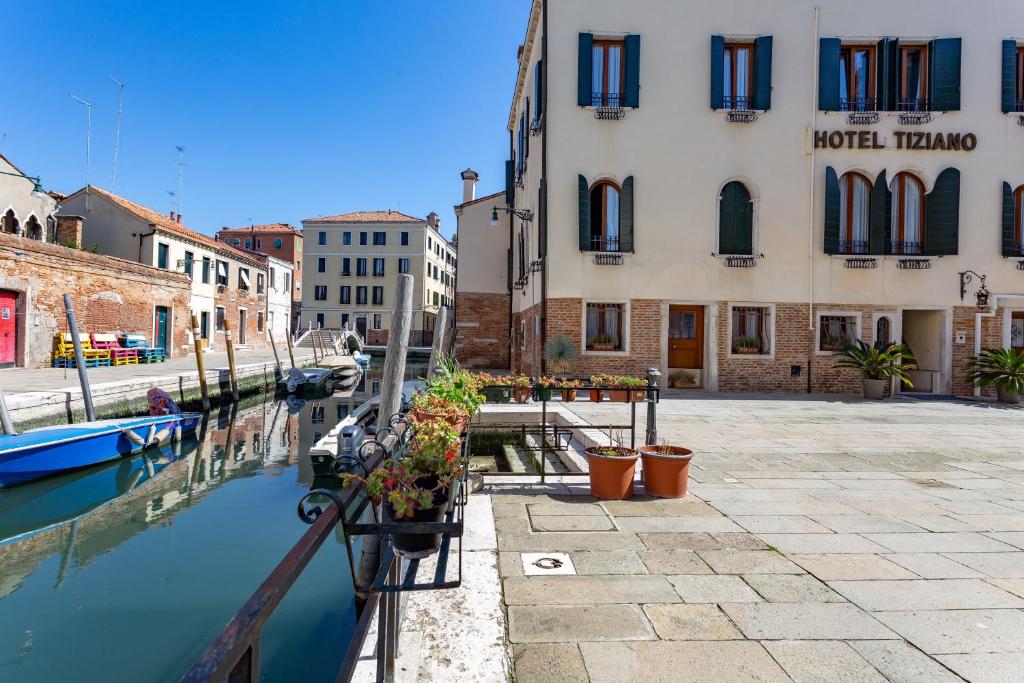 un canale in una città con edifici e piante di Hotel Tiziano a Venezia
