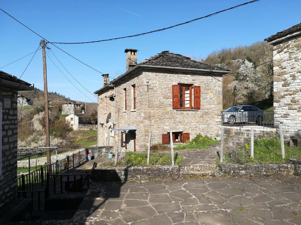 una vieja casa de piedra con un coche aparcado delante de ella en Amanitis Stone House, en Kipoi