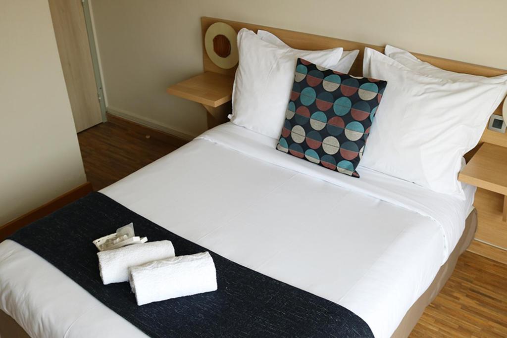 a large white bed with two towels on it at Hotel Le Transat Bleu in Dunkerque