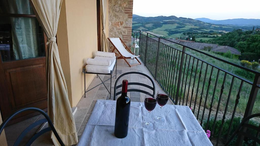 einen Tisch mit einer Flasche Wein und Gläsern auf dem Balkon in der Unterkunft Casa Panorama in Casole dʼElsa