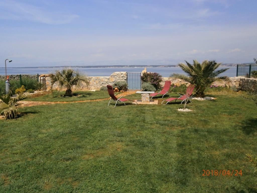 two chairs sitting in the grass near the water at PutPunte12 in Sutomišćica