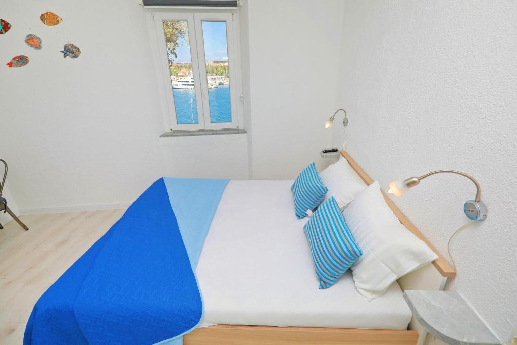 ein Bett mit blauen und weißen Kissen und einem Fenster in der Unterkunft Sea View Studio Apartment in Zadar