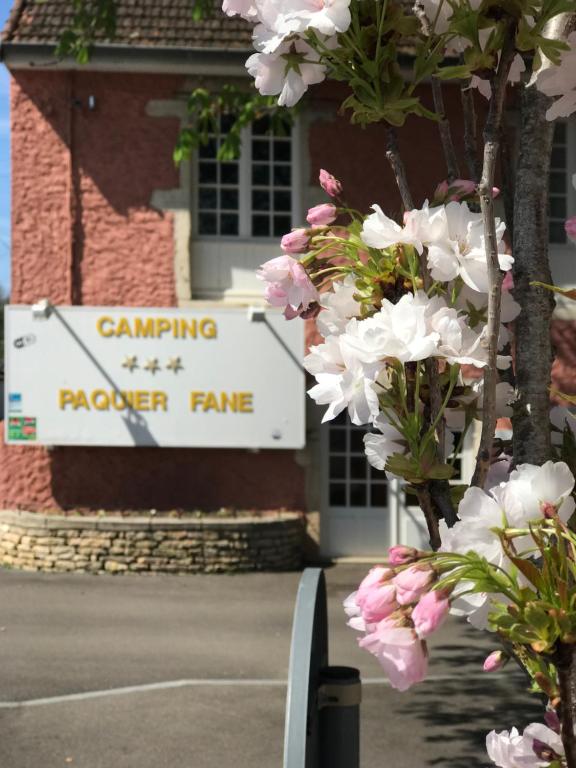 a sign in front of a building with pink flowers at Camping Du Paquier Fané in Chagny