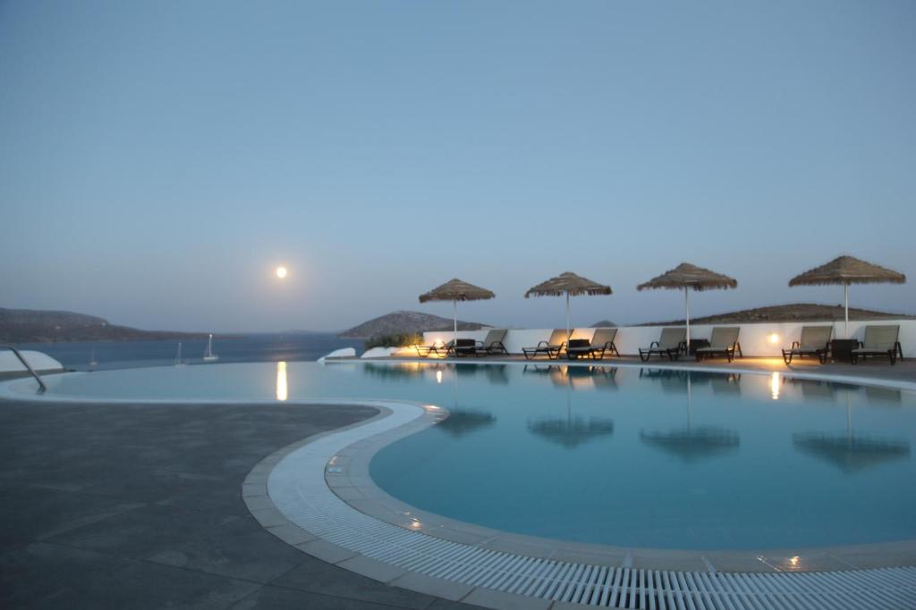 a swimming pool with chairs and umbrellas at night at Castellano Village in Maltezana