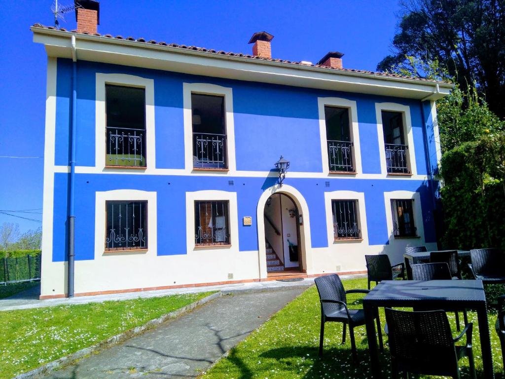ein blau-weißes Haus mit einem Tisch davor in der Unterkunft Apartamentos Rurales Inguanzo in Villanueva de Pría