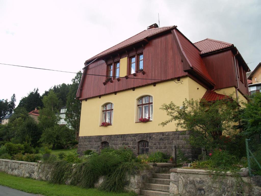 uma casa com um telhado vermelho e uma parede de pedra em U Nás em Smržovka